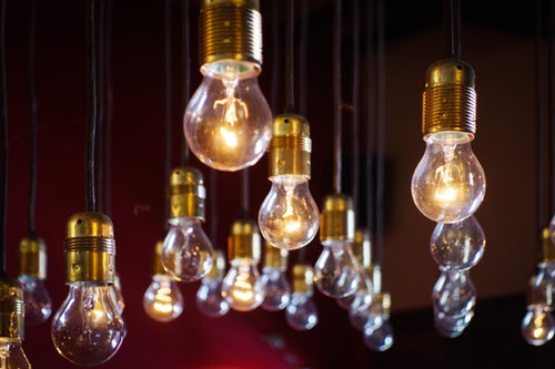 Several energy saving light bulbs handing from the ceiling on black string