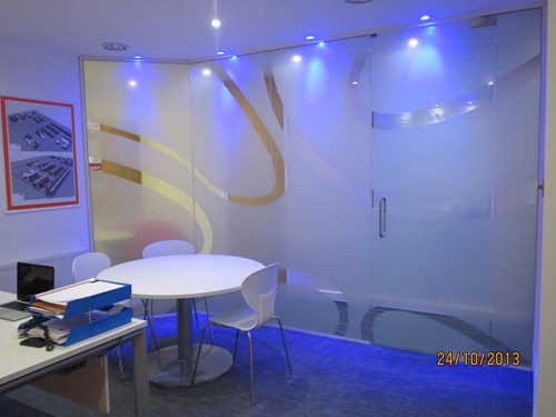 Inside a small office with blue glass partitions for office wrapped around.